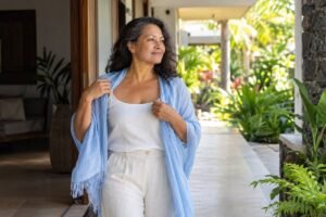 Accueil 6 Femme polynésienne d’une cinquantaine d’années dans un passage vers un jardin lumineux, pour illustrer la goutte chez la femme après la ménopause.